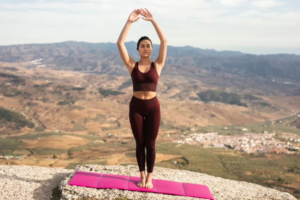 Persona practicando yoga en postura de meditación al amanecer, representando equilibrio entre cuerpo y mente
