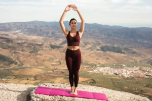 Persona practicando yoga en postura de meditación al amanecer, representando equilibrio entre cuerpo y mente